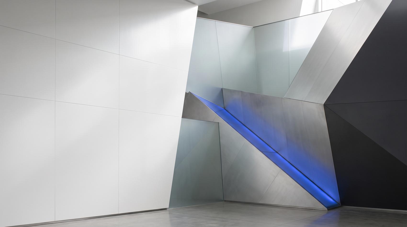 Abstract white, graphite and aluminum architecture with a controlled blue light plane